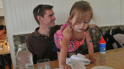 Dr. Karl Bowman talks to his wife Melissa as their daughter Emma, 2, reaches for a sweetener packet during lunch at The Porch in Schenley Park.