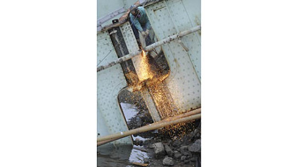 A worker puts the cutting torch to structural steel from the 31st Street Bridge after a controlled explosion.