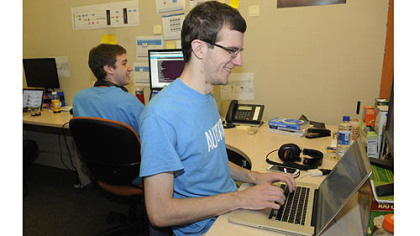 Craig Younkins, right, the chief technical officer at Autoref.com, jokes with Dillon Grove, the site's lead designer, in their office in the AlphaLab building on the South Side.
