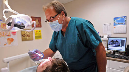 Dentist Rick Bennett, a volunteer, sees a patient at the Community Health Clinic of Butler County.