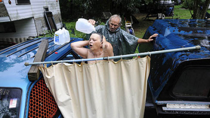 Fred McIntyre, 56, helps his wife Janet, 52, shower during a heavy rainstorm July 19.  The McIntyres usually drive 11 miles to their son's home to shower but when the weather is nice, they will set up a makeshift shower in their front yard in the Woodlands.