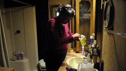 Janet McIntyre brushes her teeth with a quarter cup of carefully rationed bottled water June 4 at her home in the Woodlands.  Mrs. McIntyre was hoping to redo her bathroom and even purchased the wallpaper to spruce up the walls but water contamination prevented her from finishing the project.