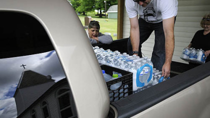 Volunteers Jason Bell and Diane Fipe load water into a pickup truck while water delivery coordinator Janet McIntyre counts up the gallons June 4 at White Oaks Springs Presbyterian Church near Evans City.
