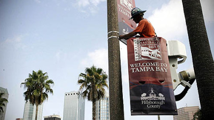 A worker begins installing banners for the Republican National Convention in front of the Tampa Bay Times Forum, in Tampa, Fla.