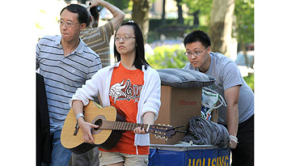 Victoria Lang strums her brother's guitar as she helps  during move-in day Tuesday at the University of Pittsburgh. Kevin Lang, right, a sophomore majoring in finance, was getting help also from father, Zig. The Lang family is from Collegeville, Pa.