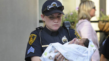 Three-day-old Bryce Coleman is carried to an ambulance by Pittsburgh police Sgt. Cristyn Zett.
