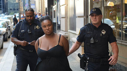 Police take a woman into custody in the Investment Building, where the abducted baby was found.