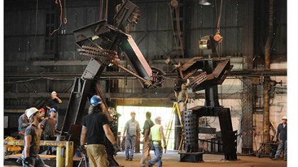 Two tall steel sculptures titled "The Workers" stand mounted at the LTV Hazelwood Plant as they are readied to be loaded for their trip to their permanent home on the South Side.