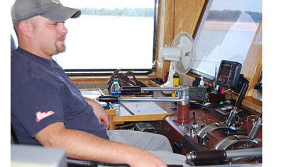 Sam Lynch, a tow boat pilot in training, at the helm of the Captain Gerald Boggs on the Mississippi River.