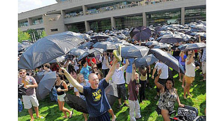 Kevin Murray of Scranton, left, cheers among other participants as more than 3,000 members of the University of Pittsburgh's incoming freshman class celebrated Gene Kelly's centenary by participating in a choreographed umbrella dance Thursday in an attempt to break a Guinness World Record on the lawn of the Petersen Events Center.
