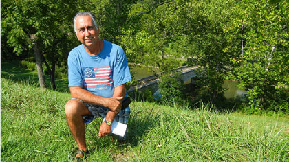 Gary Hooper of Jefferson, Md., kneels near Burnside Bridge, Antietam Battlefield. His great-great-grandfather, Abraham Burns, had served with the 52nd Virginia Infantry. That unit, part of "Stonewall" Jackson's command, had fought the Union troops trying to capture the West Woods. "I still have his bayonet," Mr. Hooper said.