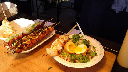 A chef preparing "Kickass Rice" -- rice with herbs and a boiled egg on top -- served with skewers of mochi -- rice cubes -- topped with cheese at the Richmond Night Market in Richmond, British Columbia.