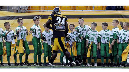 The Steelers' Rashard Mendenhall greets youth football players tonight before the start of the game against the Panthers.