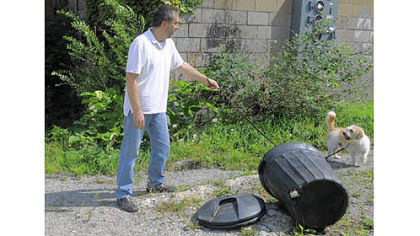 Peter Kreuthmeier and his dog Zeke in Garfield, in front of the garbage can where they discovered a neglected dog Tuesday.