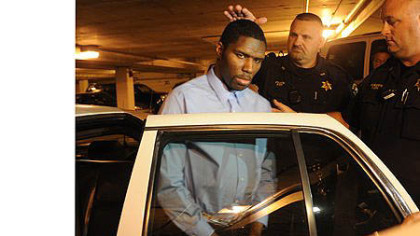 Melvin Knight is escorted to a squad car outside the courthouse Thursday.