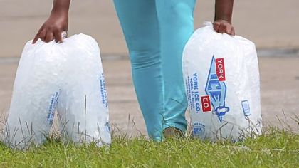A woman pauses Friday while carrying bags of ice from an aid distribution center in New Orleans for victims of Isaac. The center was one of three in the city operated by the Louisiana National Guard to assist residents, many of whom still have no electricity because of the storm.