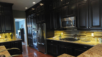 The kitchen has custom maple cabinetry topped by decorative glass-doored cabinets.