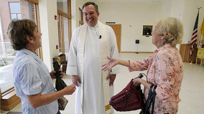 Father Dave Poecking greats parishers Nancy Gretches, left, and Deanna Schlott, both of Carnegie, before he holds the vigil Mass for the Feast of the Assumption at St. Elizabeth Ann Seton in Carnegie. This parish was part of merging that was done 20 years ago in a sweeping reorganization of the Catholic Diocese of Pittsburgh.