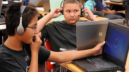 Sixth graders Ravi Embar, left, and Gage Pilone, among the 60 students enrolled in the new Pittsburgh Online Academy, get acquainted with their laptops at orientation.