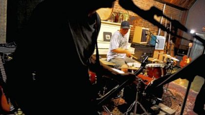 Meeka in Jail band drummer Mo Heine, behind the silhouette of Rich Snyder, rehearses Thursday at bass guitarist Jay Green's business, Big Science Music.