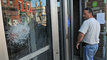 A Pittsburgh police officer looks at the shattered door of the Citizens Bank on Butler Street in Lawrenceville after a Thursday morning robbery attempt.