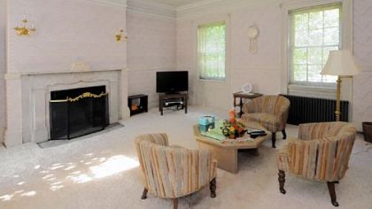 The living room features a pair of electric candelabras and white wainscoting.