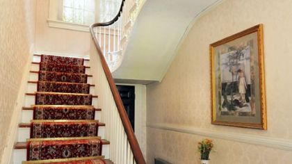 The main entry has one of the two staircases in the home (the other is located in the original structure). It has turned handrails in dark wood and carved wood panels that run to the second floor.