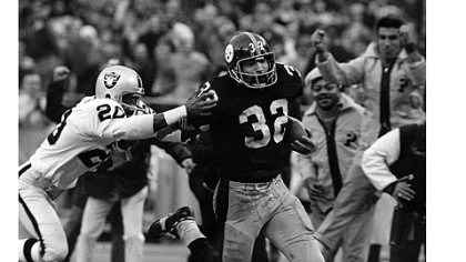 The Steelers' Franco Harris, right, eludes a tackle attempt by the Raiders' Jimmy Warren on the way to scoring on a play known as the "Immaculate Reception."