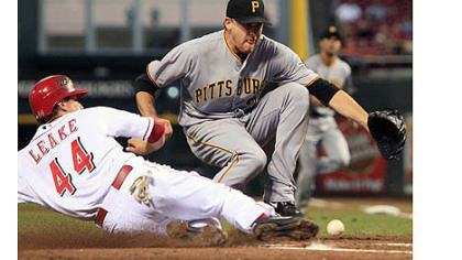 The Reds' Mike Leake scores as Pirates starting pitcher Kevin Correia reaches for the ball after Correia threw a wild pitch in the second inning.