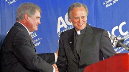 Notre Dame president Rev. John I. Jenkins, right, is congratulated by Atlantic Coast Conference commissioner John Swofford at a news conference in Chapel Hill, N.C., where it was announced that the Irish would join the ACC beginning in 2015.