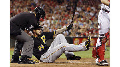 The Pirates' A.J. Burnett, center, falls to the ground after striking out with the bases loaded in the fourth inning. Home plate umpire Manny Gonzalez helps out at left.