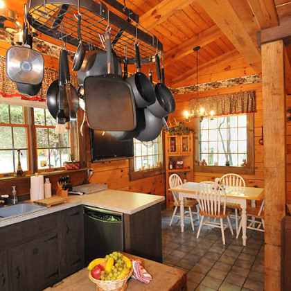 A rustic, natural-finish butcher block island is topped by a hearty pot rack filled with pots in every size and shape -- both decorative and functional.
