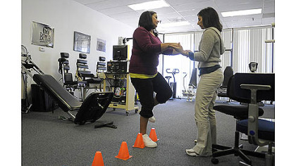 Nettie Gibson, left, who was seriously injured by a drunken driver in August 2011, does an exercise with the help of therapist Annie Ursom at East Suburban Sports Medicine in Monroeville.