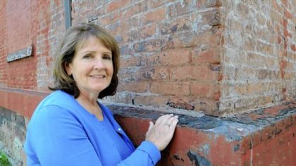 Mary Frailey Calland, author of the historical novel "Consecrated Dust," stands at Building 6 of the Allegheny County Health Department in Lawrenceville, one of four surviving buildings from the Allegheny Arsenal.