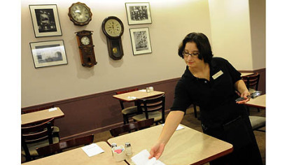 Nicole Kelsey, of Mt. Oliver, sets tables in preparation for Tuesday's re-opening of the Tic Toc Restaurant in Macy's.