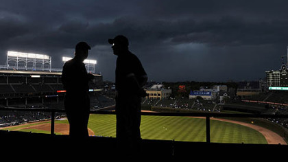 Storm clouds move over Wrigley Field as ushers look at the empty stands during a delay to the start of the game between the Pirates and Cubs tonight in Chicago.