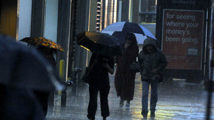 Commuters huddle beneath their umbrellas along Fifth Avenue early Tuesday morning.