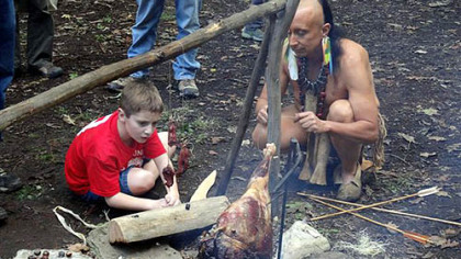 Todd Johnson helps a young boy make his first flint-tipped hunting arrow.