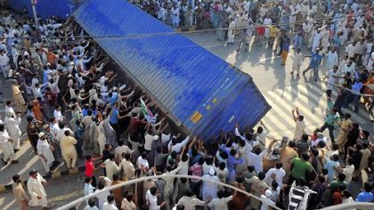 Pakistani Muslim demonstrators topple a freight container, placed by police in Lahore as a roadblock during a protest against an anti-Islam film.