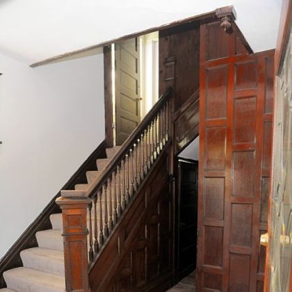 The entry features wood paneling and a staircase that has the original wood finish.