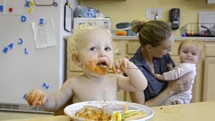Sawyer Farrell, 1, eats his lunch while his mother and head teacher for his infant class, Ashley Farrell tends to nine-month-old Katelyn Houk Thursday at the Glen Montessori School in Ross.