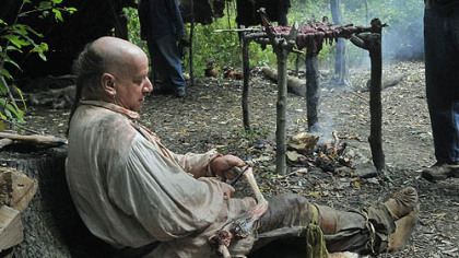 With the meat from a deer smoking over a fire, Ed Robey, of Morgantown, W.Va., skins a deer leg at the American Indian Heritage Festival on Sunday at Meadowcroft Rockshelter.
