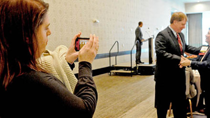 Amie Downs, Allegheny County Executive Rich Fitzgerald's communications director, uses the camera on her phone to snap a photo of Mr. Fitzgerald on Wednesday from his talk to property agents before the Downtown Real Estate Tour at the Fairmont Hotel.