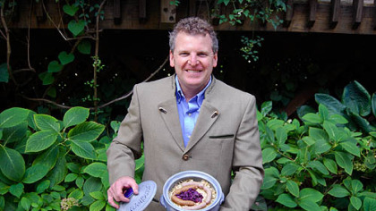 Kevin Kirkland in trachtwear holding his own version of Choucroute garnie, an Alsatian dish that combines sausage, potatoes and sauerkraut.
