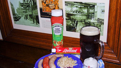 Wurst plate includes (left to right): Nurnberger bratwurst, knackwurst, bratwurst, sauerkraut and rottkraut. In background is curry ketchup, extra spicy mustard and Iron City Amber beer. Photos in frame are of Carl Meyer's Hof in Buffalo, N.Y.