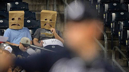 Pirate fans show their frustration with a record 20 losing seasons. Braves pitcher and former Pirate Paul Maholm is in the foreground.