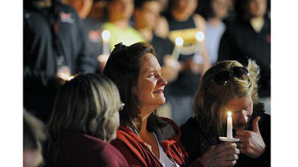 Denise McNerney, mother of slain Washington & Jefferson football player Tim McNerney, holds a candle at a vigil in front of members of the football team.