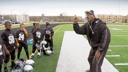 A coach gives a pep talk to some young football players in a scene from Steve James' "Head Games."