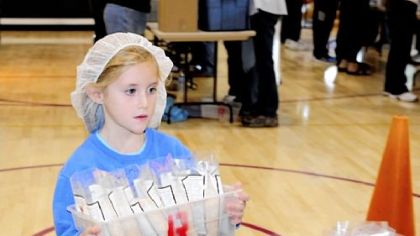 Kendall Smith helps pack meals Saturday at Christ United Methodist Church in Bethel Park. Kendall's role was to carry items across the gym.