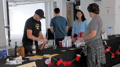 Kevin Cox of Bar Marco, left, with Skye Frontier and Abbie Maravalli, both of Epic Development, wait on a customer at the Tapped pop-up beer garden at Bakery Square Sept. 29.